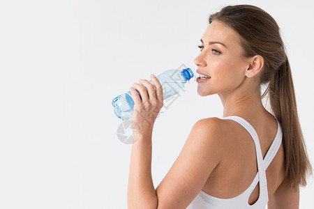 女人用蓝色瓶子喝水美丽合身的女人喝水蓝色的瓶子白色的背景图片