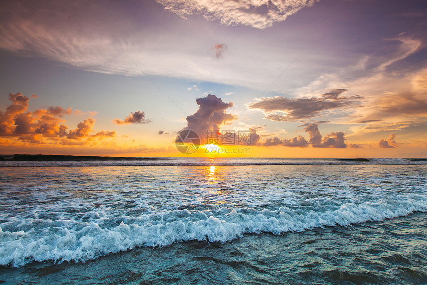 日落海洋上美丽的日落天空背景前溅海浪图片