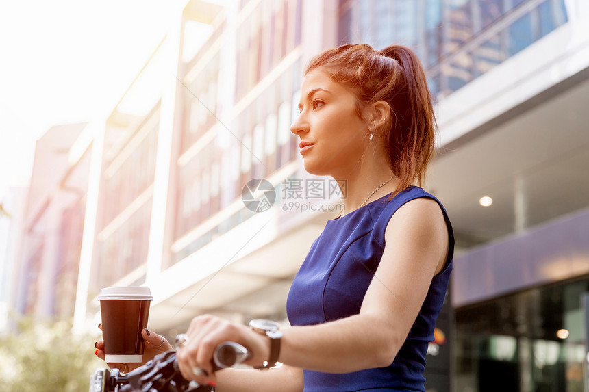 轻的女人骑自行车上下商务青妇女骑自行车喝杯咖啡图片