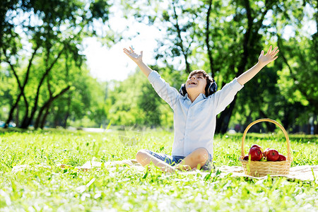 夏天公园里的小快乐男孩戴着耳机大自然的声音背景图片