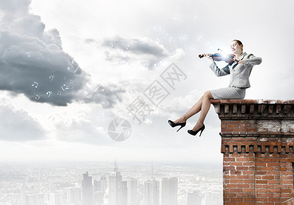 女小提琴手轻的女商人坐建筑物的顶部拉小提琴背景图片