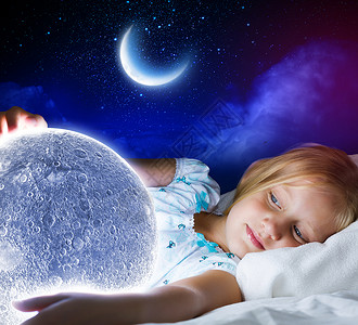 晚安女孩躺床上,手里着月亮微笑高清图片素材