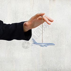 商务旅行特写商人手飞机模型绳子上图片