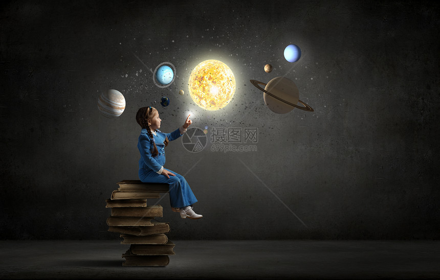 小女孩探索太空小女孩坐叠书上,触摸着星球图片