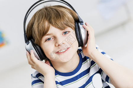 可爱的男孩戴着耳机享受音乐背景图片