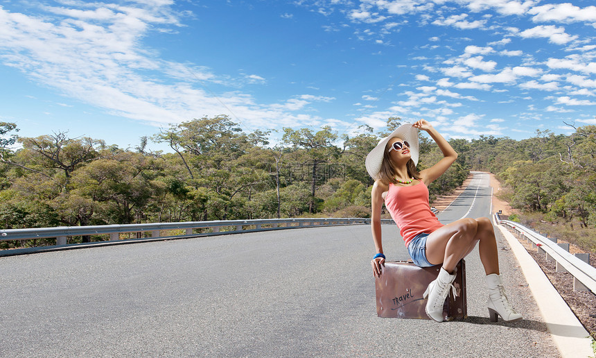 自动启动旅行轻漂亮的女孩旅行者坐路边的手提箱上图片