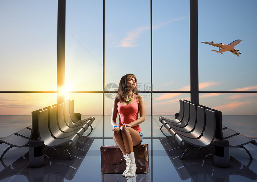 暑假旅行轻漂亮的女孩旅行者机场坐手提箱上图片