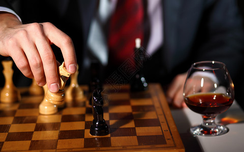 个穿深色西装的商人下棋的形象背景图片