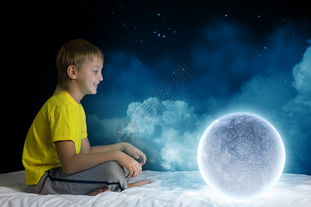 月亮上孩子晚上梦可爱的男孩坐床上梦见月亮背景