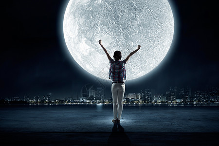 满月轻女人的后视镜,举手看着天空中的月亮图片