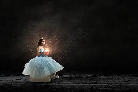 她可爱的公主小女孩公主穿着蓝色的连衣裙,头上戴着王冠,手里着红色的心图片