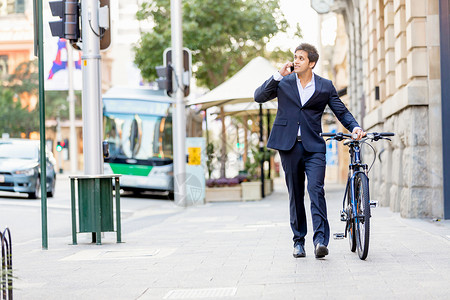 成功的商人骑自行车成功的商人穿着西装骑自行车着手机背景图片
