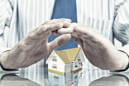 房地产保险商人的手,小心翼翼地盖住房子的模型图片素材