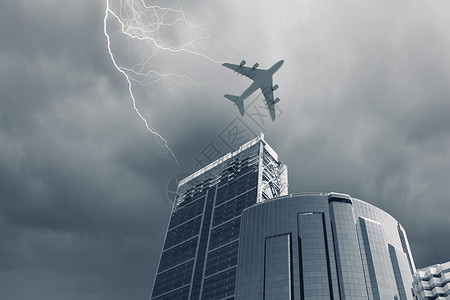 飞行飞机飞机摩天大楼上方飞行的底部视图背景图片