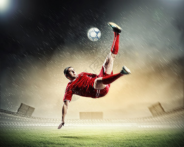 足球运动员击球足球运动员穿着红色衬衫雨中体育场击球背景图片