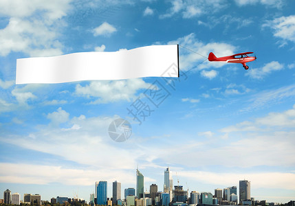 飞机拉着横幅飞跃城市上空背景图片