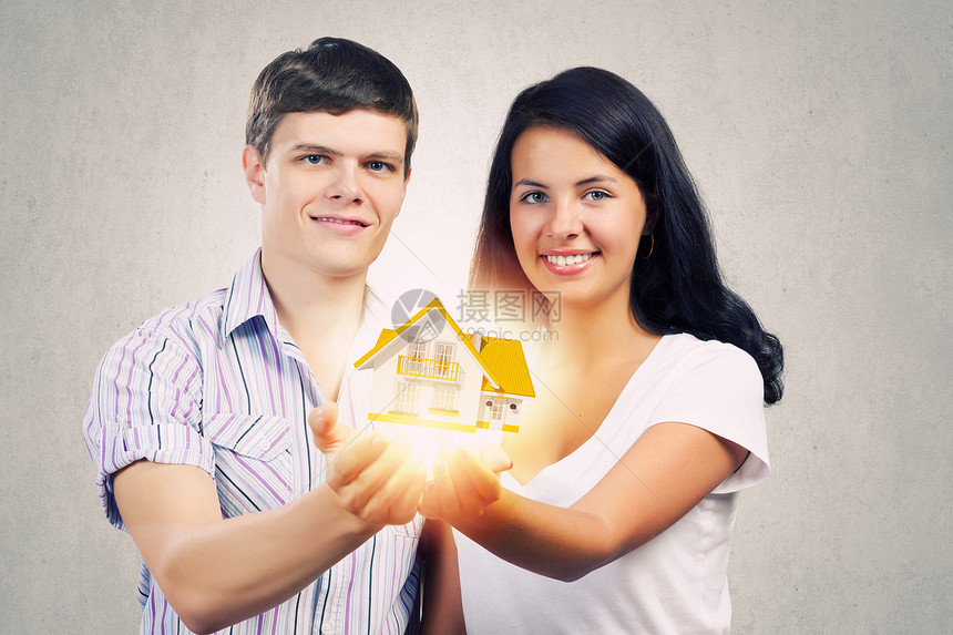 轻的家庭幸福的轻夫妇把房子的模型放手掌上图片