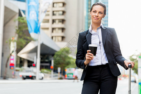 商务女士拉着手提箱城市里散步轻的商务女士拉着手提箱城市里散步图片