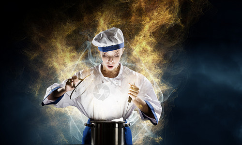 她厨师的魔术师漂亮的女人穿着帽子围裙饭,锅上魔术图片