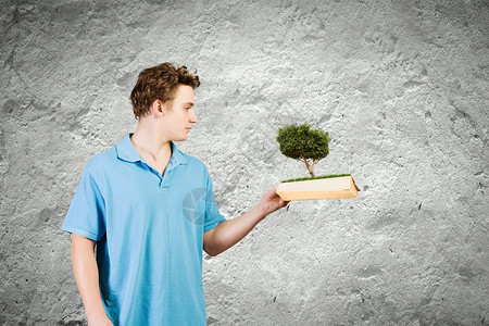 书的人轻人漫经心地着本绿树开的书图片