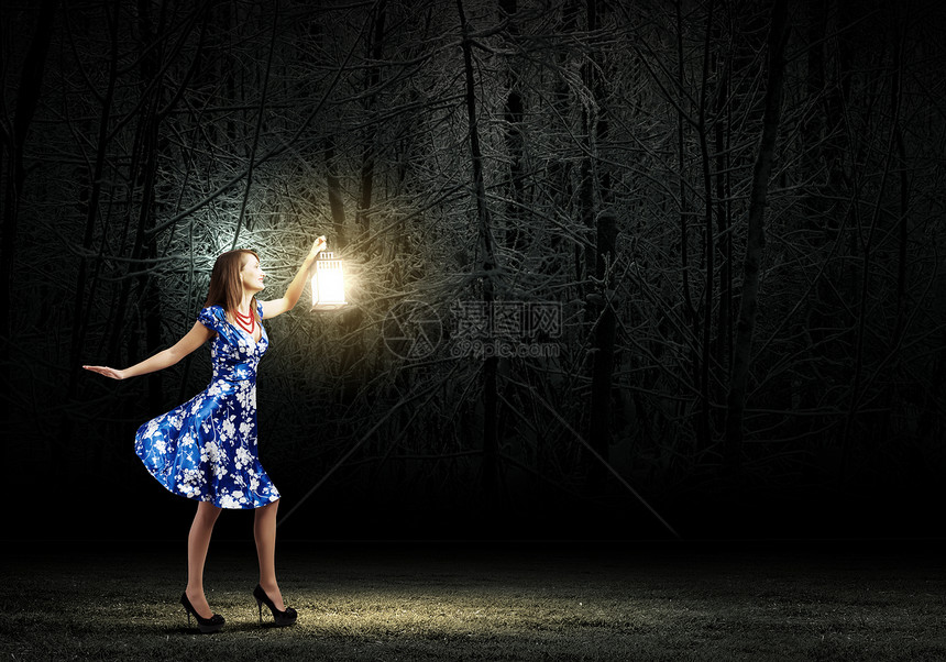 带灯笼的女人穿着蓝色连衣裙的轻女人夜间树林里散步图片