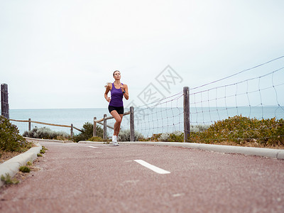 运动的年轻女人在海边跑步图片