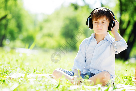 夏天公园里的小快乐男孩戴着耳机大自然的声音背景图片