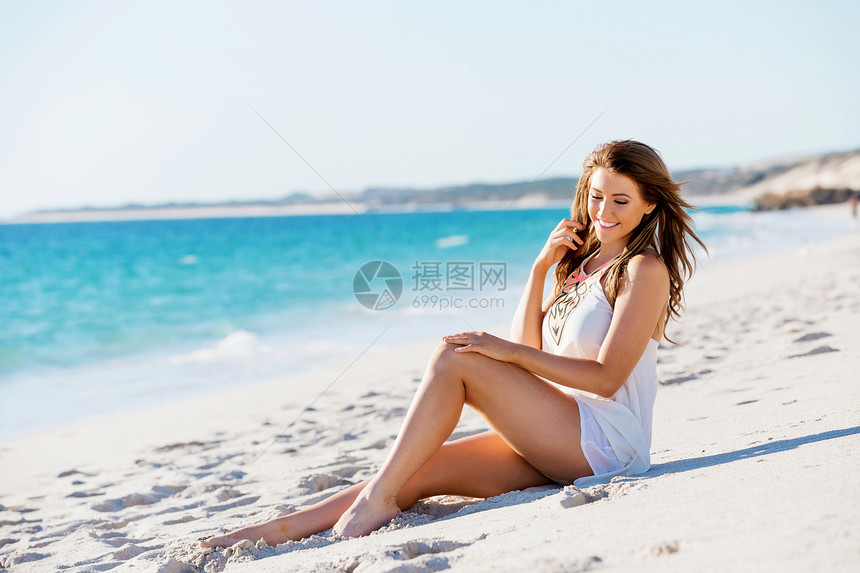 轻的女人坐海滩上坐海滩上的轻漂亮女人的肖像图片