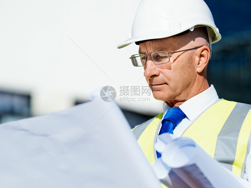 建筑工地的工程师建设者工程师建筑工人施工场景穿着带蓝图的安全背心图片