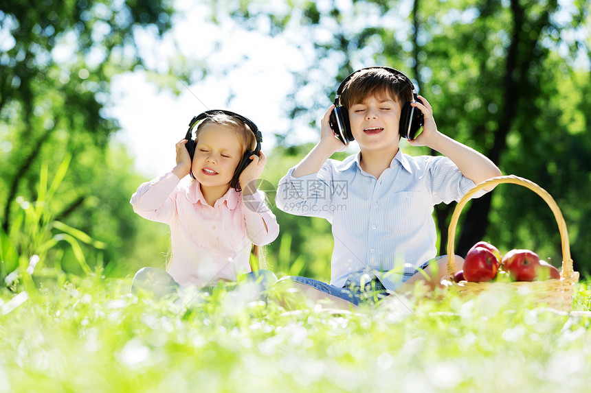 夏天公园里可爱的男孩女孩听音乐暑假周末图片