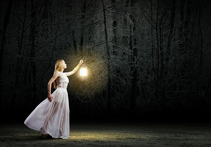 带灯笼的女人走夜间的树林背景图片