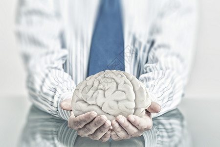 保护心理健康小心地握住人类大脑的手背景图片