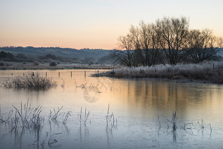 美丽的英国乡村湖泊形象与霜冻冰湖冬季日出背景图片