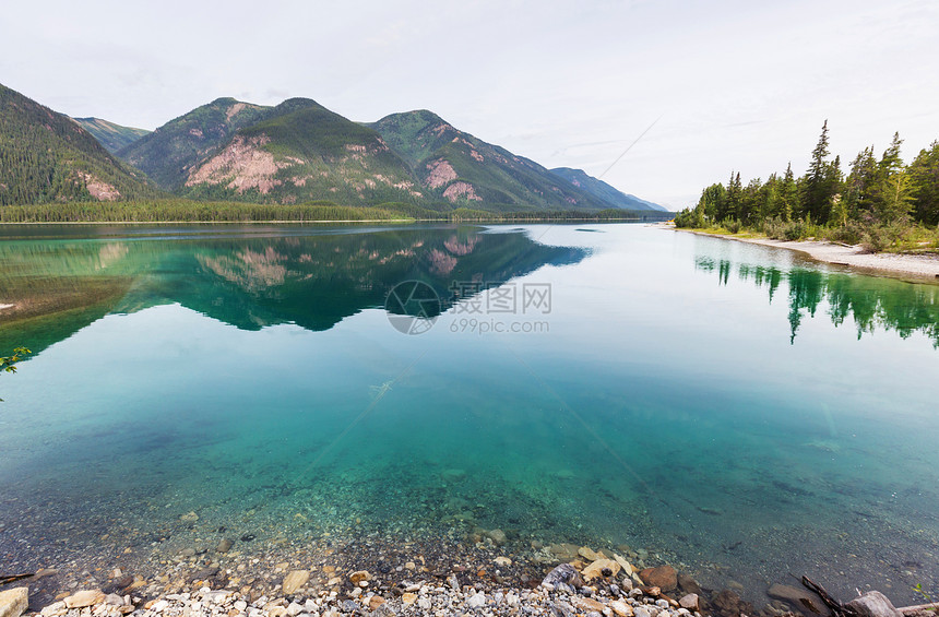 平静的景色加大的山湖旁边,岩石平静的水中反射图片