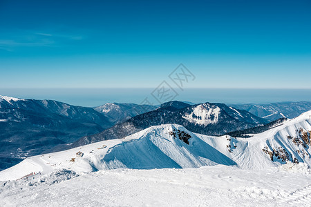 冬天的山景阳光明媚的日子里,高加索山脊上覆盖着雪克拉斯纳亚多拉那,索契,俄罗斯背景图片