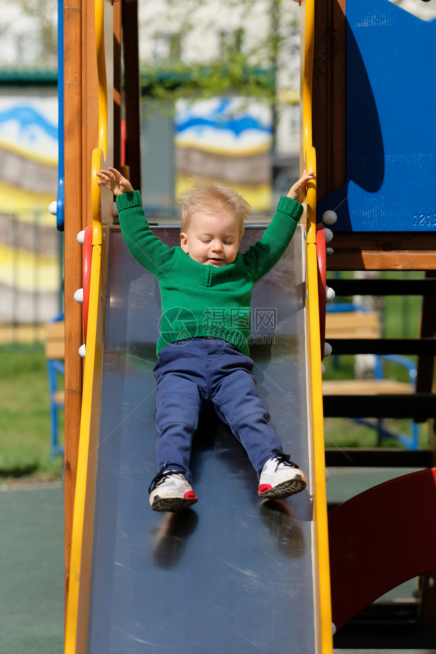 户外幼儿的肖像岁的小男孩穿着绿色毛衣操场滑梯上图片