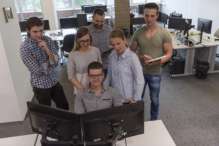 群轻的创业公司的人办公室工作时队站办公桌上图片