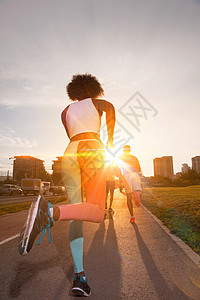 轻的黑人女孩慢跑美丽的早晨,太阳升城市的街道上背景