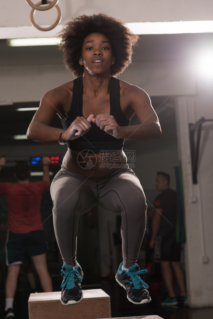 适合轻的非裔美国妇女盒子跳跃个交叉健身风格的健身房女运动员正健身房表演跳箱图片