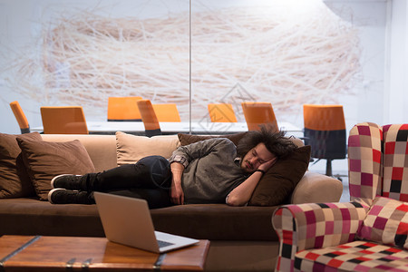 位轻的休闲商人创意办公室休息时睡沙发上图片