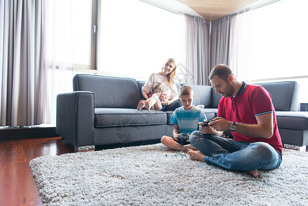 幸福的家庭爸爸妈妈孩子们玩电子游戏,爸爸儿子地板上玩电子游戏背景图片