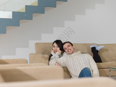 丹嫩沙多轻的多民族夫妇豪华客厅的沙发上放松背景