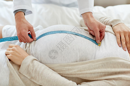 怀孕,医学,保健人们的密切产科医生与厘米磁带测量孕妇肚子医院背景图片