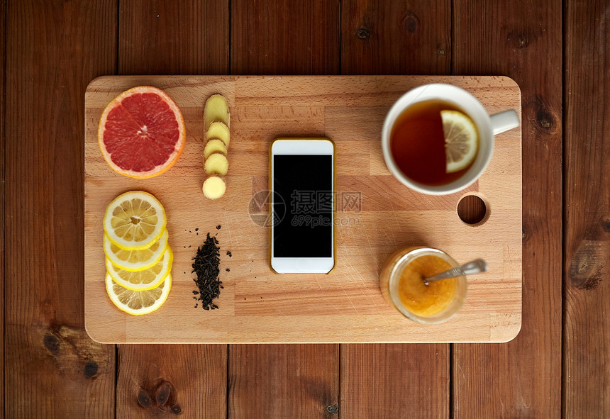 健康,传统医学,民间补救民族科学智能手机与杯姜茶,蜂蜜柑橘木板上图片