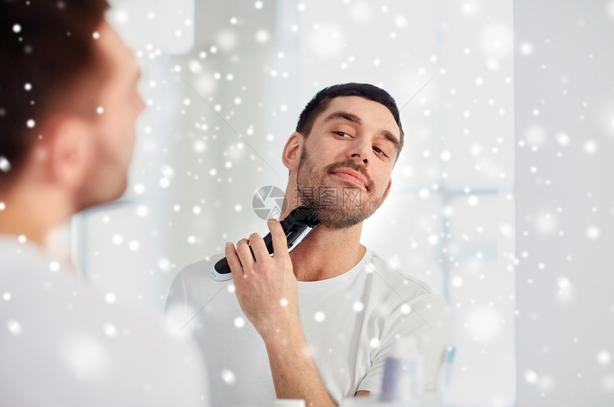 美容,冬天,诞节人们的轻人看着镜子剃须胡须与修剪机电动剃须刀家里浴室雪图片