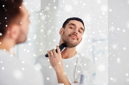 美容,冬天,诞节人们的轻人看着镜子剃须胡须与修剪机电动剃须刀家里浴室雪图片