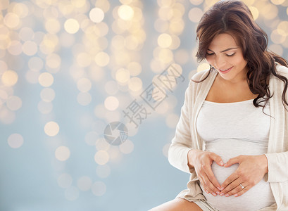 怀孕,爱,人期望的快乐的孕妇节日灯光背景上心脏手势背景图片