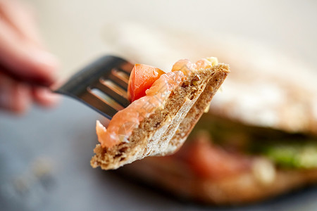 食物,晚餐人的人的手吃鲑鱼帕尼尼三明治与西红柿奶酪用叉子刀餐厅图片