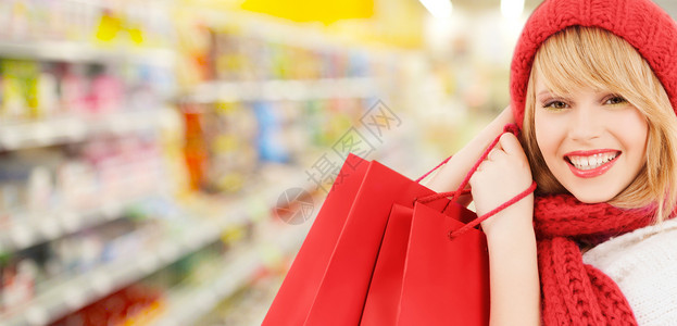 人们,寒假,销售消费主义的快乐的微笑女人戴着红色的帽子围巾,超市背景下许多购物袋漂亮的高清图片素材