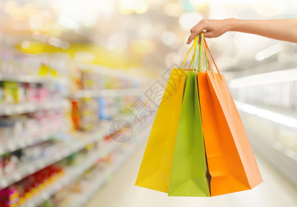 人,消费主义销售手与购物袋超市背景图片